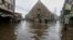 FILE - People wade through a flooded road after heavy rains, in Karachi, Pakistan, July 25, 2022.