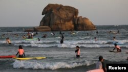 FILE - Surfers are seen in the sea in Sanya, Hainan province, China, Nov. 26, 2020. With some 80,000 tourists visiting the resort city, authorities imposed a lockdown on Aug. 6, 2022, in an effort to stem a COVID-19 outbreak.