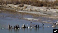 ARCHIVO - Afganos intentan reparar una presa en un río, como se ve desde la base de operaciones de las fuerzas británicas Sterga II, en diciembre de 2013, en la provincia de Helmand, en el sur de Afganistán.