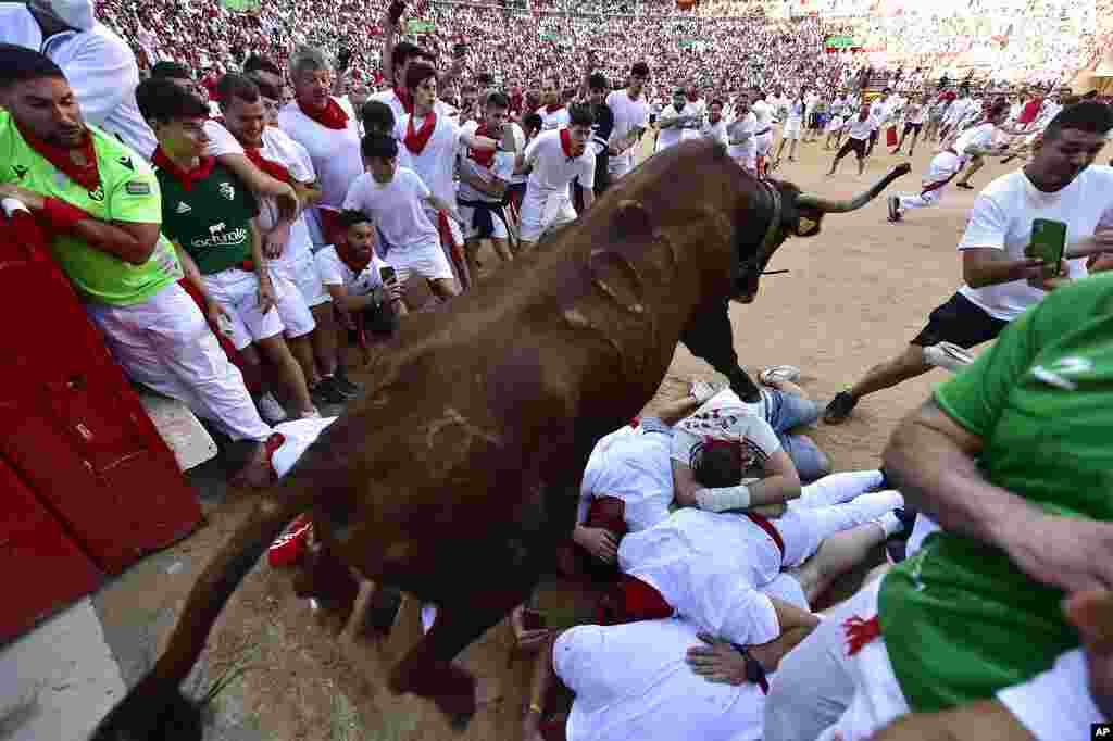 A fighting bull jumps over runners entering the bullring during the running of the bulls at the San Fermin Festival in Pamplona, northern Spain.