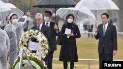 جاپان کے وزیراعظم فومیو کشیدا اور امریکہ کے سفیر رحم ایمونئول ہیروشیما کے پیس میموریل پارک میں ایک یادگار پر پھول چڑھا رہے ہیں (رائٹرز)