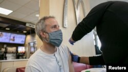 FILE: A man receives a booster shot for the coronavirus disease (COVID-19) at a McDonald's as the Omicron variants spreads through the country in Chicago, Illinois, U.S., 12.21.2021