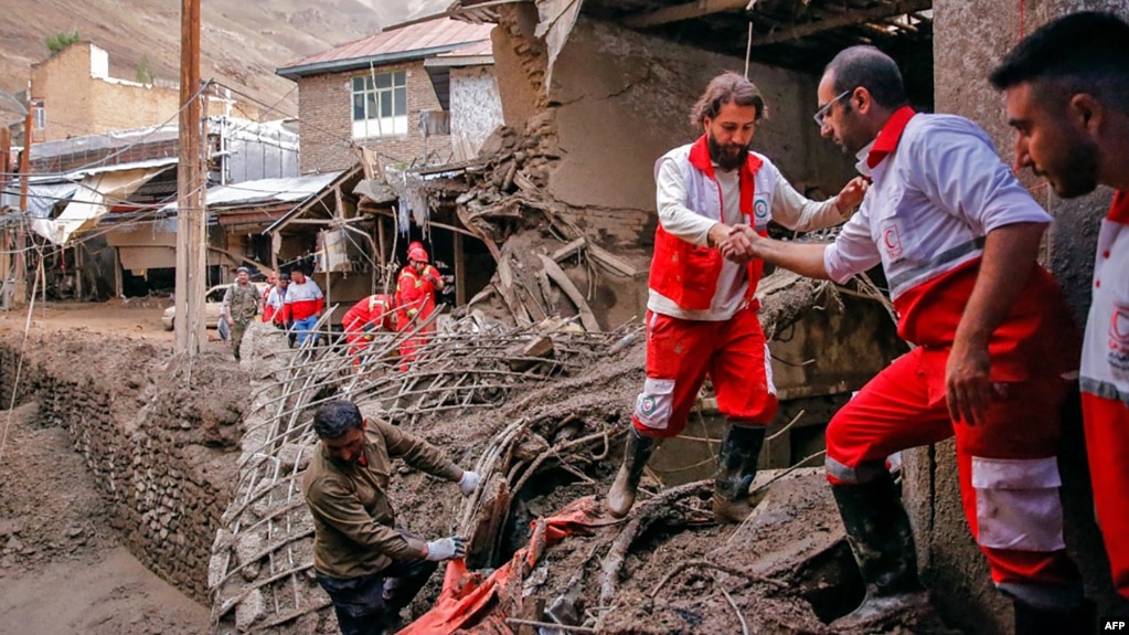 A handout picture provided by the Iranian Red Crescent shows members of a rescue team working at the site of a flash flood in Imamzadeh Davood, northwest of Tehran, July 29, 2022.