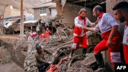 A handout picture provided by the Iranian Red Crescent shows members of a rescue team working at the site of a flash flood in Imamzadeh Davood, northwest of Tehran, July 29, 2022.