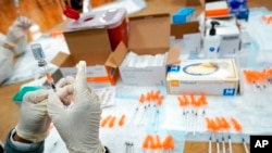 FILE - A nurse fills a syringe with a COVID-19 vaccine at a pop up vaccination site in the Staten Island borough of New York, April 8, 2021.