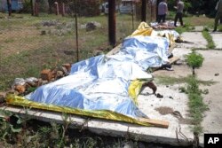 Investigators examine bodies of Ukrainian military prisoners at a prison in Olenivka, in an area controlled by Russian-backed separatist forces, eastern Ukraine, July 29, 2022.