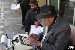 Rogelio Condori mengetik di sebelah seorang perempuan Aymara di jalan di La Paz, Bolivia, 8 Juni 2022. (Martín SILVA / AFP)