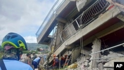 Rescatistas intentan sacar a un residente atrapado debajo de una estructura derrumbada después de que un fuerte terremoto sacudiera La Trinidad, provincia de Benguet, norte de Filipinas, el miércoles 27 de julio de 2022. (Oficina de Protección contra Incendios vía AP)