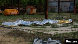 Обгорілі тіла в'язнів лежать накриті після обстрілу в СІЗО в селищі Оленівка Донецької області, Україна, 29 липня 2022 року.