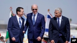 Presiden Joe Biden diapit Perdana Menteri Israel Yair Lapid (kanan) dan Presiden Isaac Herzog (kiri) setibanya di Bandara Ben Gurion, Tel Aviv, Rabu, 13 Juli 2022. (AP/Evan Vucci)