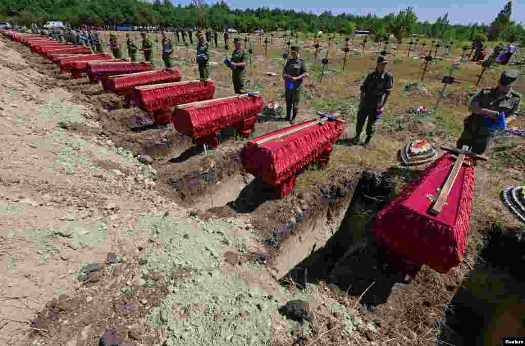 Service members stand near the coffins during a funeral for 58 unidentified soldiers of the self-proclaimed Luhansk People's Republic who were killed in 2022 during the Ukraine-Russia conflict, in Luhansk, Ukraine.