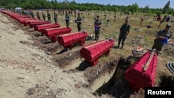 Service members stand near the coffins during a funeral for 58 unidentified soldiers of the self-proclaimed Luhansk People's Republic who were killed in 2022 during the Ukraine-Russia conflict, in Luhansk, Ukraine.