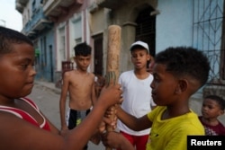 Kevin Kindelan (R), 8, plays baseball with friends in downtown Havana, Cuba, July 18, 2022. (REUTERS/Alexandre Meneghini)