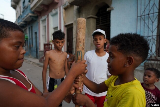 Kevin Kindelan (R), 8, plays baseball with friends in downtown Havana, Cuba, July 18, 2022. (REUTERS/Alexandre Meneghini)