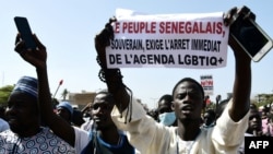 FILE — A man holds a sign reading 'No to LGBT agenda' during a protest called by religious associations against homosexuality on May 23, 2021, on the Obelisque square in Dakar.