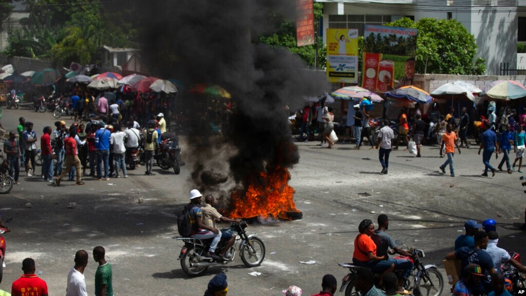People walk around burning tires set up by taxi drivers to protest the country's fuel shortage in Port-au-Prince, Haiti, July 13, 2022.