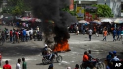 People walk around burning tires set up by taxi drivers to protest the country's fuel shortage in Port-au-Prince, Haiti, July 13, 2022.