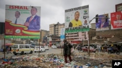 FILE - A man scavenges through rubbish below campaign posters for local government candidates in the Mathare low-income neighborhood of Nairobi, Kenya, Aug. 1, 2022. 