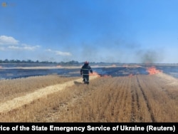 A firefighter is seen in a field, which burns after a military strike in Mykolaiv region, Ukraine, in this handout picture released July 27, 2022.