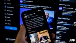 In this photo illustration taken on July 21, 2022, a tweet from U.S. President Joe Biden saying "Folks, I'm doing great" is seen on a cell phone with a breaking news alert that the president has positive for the coronavirus.