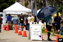 FILE - People line up at a monkeypox vaccination site, in Encino, Calif., , July 28, 2022.