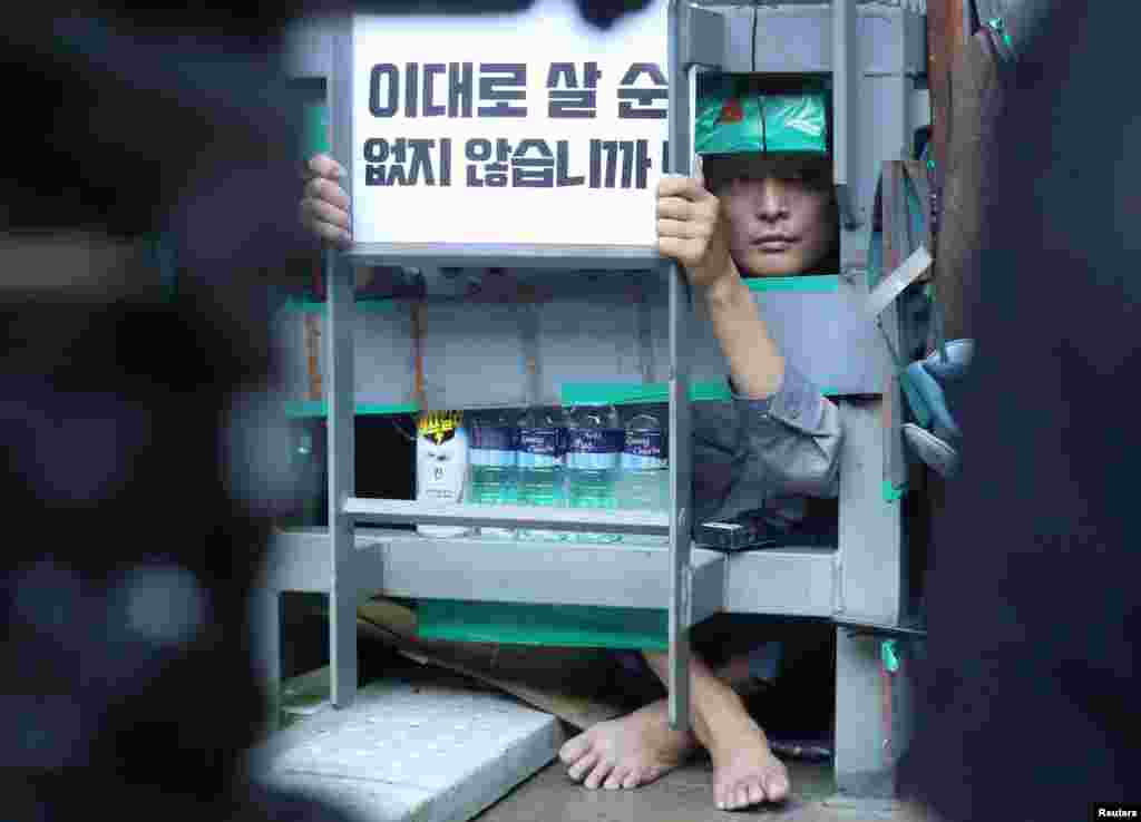 Yoo Choi-ahn, vice chief of the subcontractor union, attached inside a steel cage-like structure that he welded himself to on the floor of the occupied oil tanker, holds a sign during a strike at Daewoo Shipbuilding &amp; Marine Engineering in Geoje, South Korea, July 19, 2022.