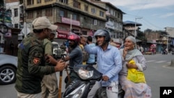 Kashmiri motorists seek permission from policemen to cross a road near a checkpoint during restrictions in Srinagar, Indian controlled Kashmir, Aug. 7, 2022.