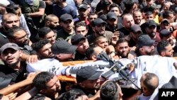Mourners carry the body of one of two Palestinians killed earlier in confrontations with Israeli troops in the old quarter of the West Bank city of Nablus, during their funeral procession in the same city, on July 24, 2022. 