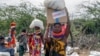 (FILE) Locals residents carry a boxes and sacks of food distributed by USAID, in Kachoda, Turkana area, northern Kenya, Saturday, July 23, 2022.