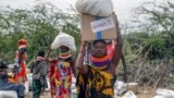 (FILE) Locals residents carry a boxes and sacks of food distributed by USAID, in Kachoda, Turkana area, northern Kenya, Saturday, July 23, 2022.
