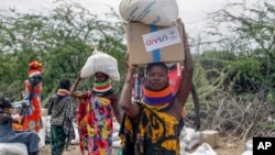 (FILE) Locals residents carry a boxes and sacks of food distributed by USAID, in Kachoda, Turkana area, northern Kenya, Saturday, July 23, 2022.