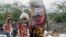 (FILE) Locals residents carry a boxes and sacks of food distributed by USAID, in Kachoda, Turkana area, northern Kenya, Saturday, July 23, 2022.