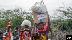 Lokalni stanovnici nose kutije i vreće hrane koje distribuira Američka agencija za međunarodni razvoj (USAID), u Kachodi, oblast Turkana, severna Kenija, u subotu, 23. jula 2022.