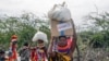 Locals residents carry a boxes and sacks of food distributed by the United States Agency for International Development (USAID), in Kachoda, Turkana area, northern Kenya, Saturday, July 23, 2022. 