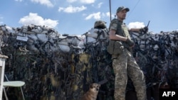 A Ukrainian soldier, accompanied by a dog, keeps position on the front line in Mykolaiv region on July 23, 2022, amid the Russian invasion of Ukraine.