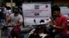 Motorists wait next to a banner that says only those vehicles with QR codes will be given fuel at a fuel station in Colombo, Sri Lanka, Aug. 1, 2022. 