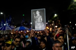 Seorang pria memegang foto mendiang mantan ibu negara Argentina Maria Eva Duarte de Peron, lebih dikenal sebagai "Evita" di luar gedung Kementerian Pembangunan Sosial di Buenos Aires, Argentina, Selasa, 26 Juli 2022. (AP /Natacha Pisarenko)