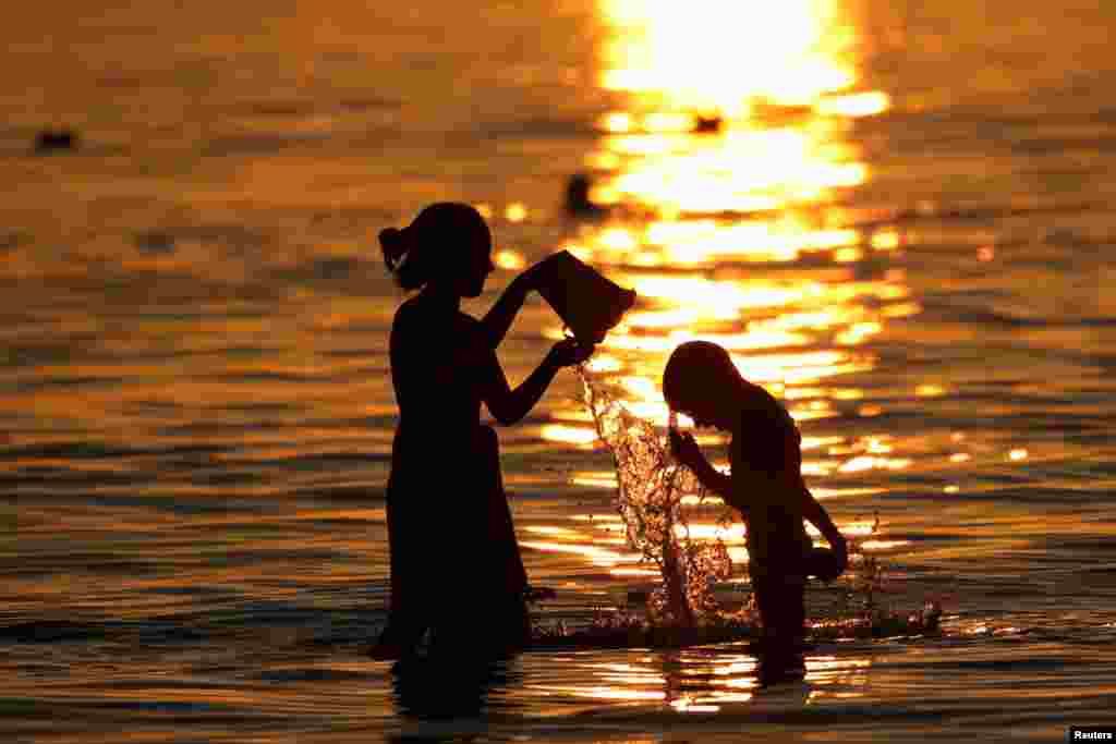 Children cool off during sunset as temperatures rise in Vlora, Albania, July 16, 2022. 