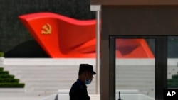 Seorang penjaga keamanan berdiri di dekat patung bendera Partai Komunis China di Museum Partai Komunis China pada 26 Mei 2022, di Beijing.(Foto: AP)