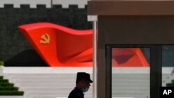 FILE - A security guard stands near a sculpture of the Chinese Communist Party flag at the Museum of the Communist Party of China on May 26, 2022, in Beijing.