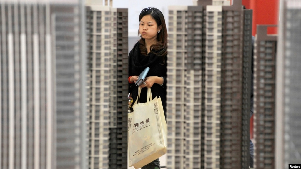 资料照：湖北武汉一名女子正在一个新楼盘售楼处观看。(photo:VOA)