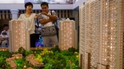 资料照：北京市民在房地产交易会上观看公寓楼模型。（2010年6月24日）
