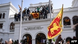 Para demonstran meneriakkan slogan dan mengibarkan bendera Sri Lanka dalam aksi protes anti-pemerintah di dalam gedung kantor perdana menteri Sri Lanka di Kolombo, 13 Juli 2022. (Arun SANKAR / AFP)