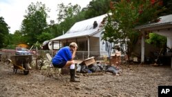 Teresa Reynolds sits exhausted as members of her community clean the debris from their flood-ravaged homes at Ogden Hollar in Hindman, Ky., July 30, 2022.