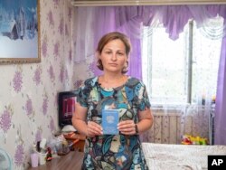 Lyudmila Bolbad, an evacuee from Mariupol, Ukraine, holds her Russian documentation in her hotel room in Khabarovsk, Russia, on Monday, July 18, 2022. (AP Photo)