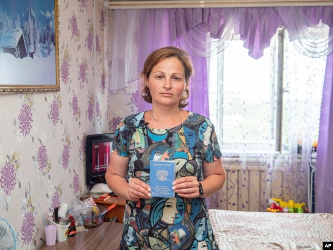Lyudmila Bolbad, an evacuee from Mariupol, Ukraine, holds her Russian documentation in her hotel room in Khabarovsk, Russia, on Monday, July 18, 2022. (AP Photo)