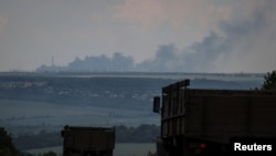 우크라이나 동부 도네츠크 주 도심 지역에서 포격으로 짙은 연기가 공중에 퍼지는 가운데 트럭들이 이동하고 있다. (자료사진)