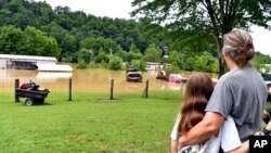Bonnie Combs, djathtas, përqafon mbesën e saj 10-vjeçare Adelynn Bowling, ndërsa prona e saj mbulohet nga uji në Jackson, Kentaki (28 korrik 2022)