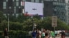 Pedestrians walk past a giant screen broadcasting news report on Chinese People's Liberation Army's (PLA) military exercises around Taiwan, in Beijing, China August 4, 2022.