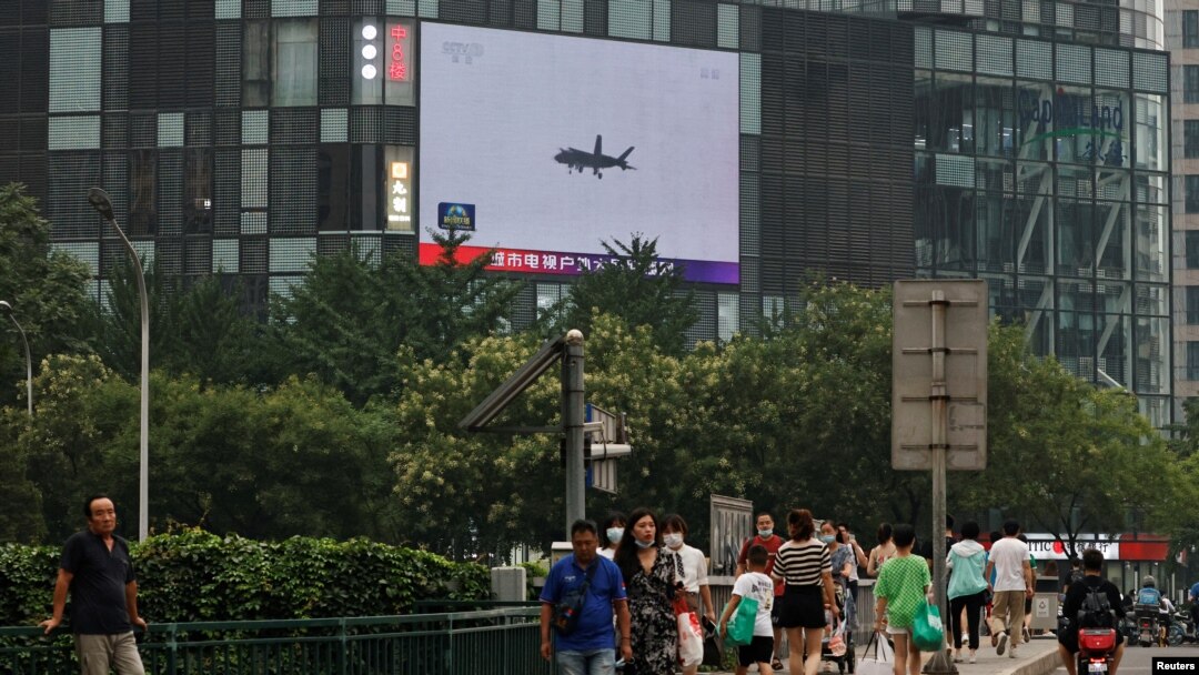 Pedestrians walk past a giant screen broadcasting news report on Chinese People's Liberation Army's (PLA) military exercises around Taiwan, in Beijing, China August 4, 2022.